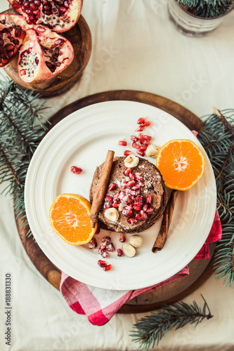 Chocolate banana pancakes with pomegranate and mandarin, winter vegan breakfast..New Year Christmas background. Top view.