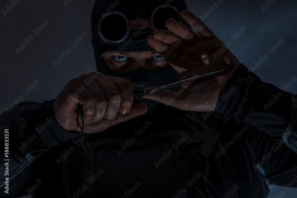 Armed spy in bulletproof vest. A military knife is prepared for a strike. Close-up.