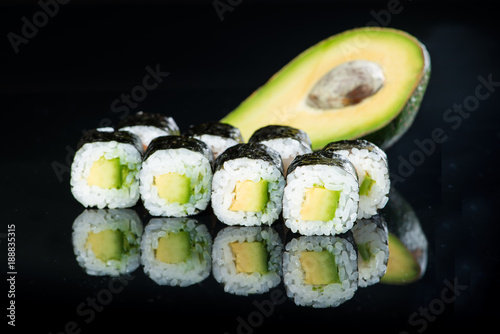 Fresh delicious Japanese sushi with avocado on dark background