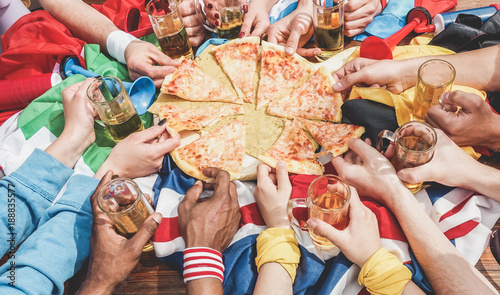 Hands top view of football supporter sharing pizza and drinking half pint beers