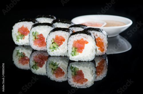 Japanese cuisine. Appetizing maki sushi rolls with rice, salmon, salmon and cucumber on dark background