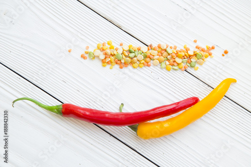 Preparing Healthy Food, Vegeterian, Vegan Concept. White wooden background with red and yellow cayenne peper and colorful beans scattered on the table, close up, copy space, top view