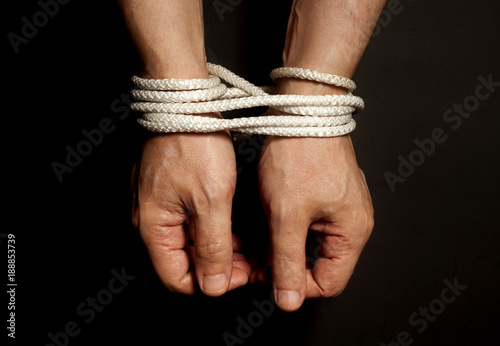 Male hands bound with rope.