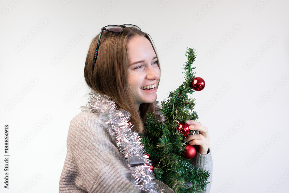 girl with a small Christmas tree hugs and smiles girl with a small Christmas tree hugs and smiles