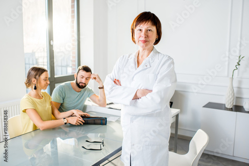 Wallpaper Mural Portrait of a senior woman doctor standing with young couple of patients in the white office Torontodigital.ca