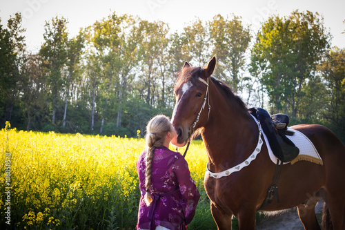 Frau mit langem Zopf küsst Shire Horse vor Rapsfeld © annebe