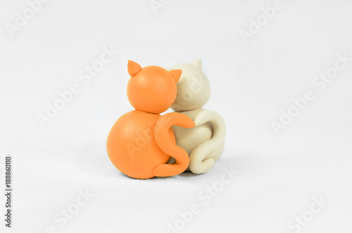Two minimalistic animal figures in love. Lovely cat plasticine models having tails in heart shape isolated on white grey background. Happy Valentine's Day in minimalism style.