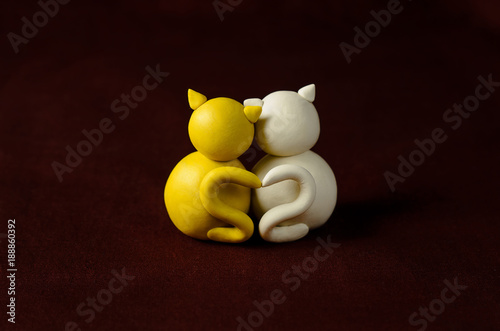 Obraz na płótnie Two minimalistic animal figures in love. Lovely cat plasticine models having tails in heart shape isolated on dark red background. Happy Valentine's Day in minimalism style. w salonie