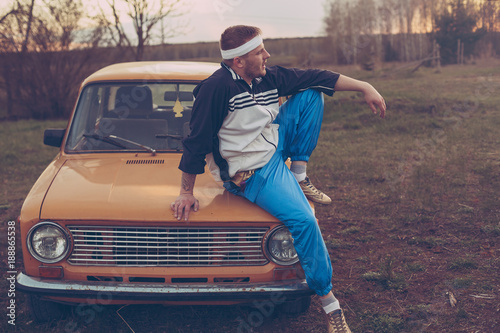 guy in the nineties lies on the hood of an old car