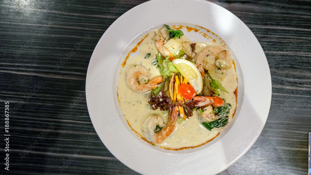 Creamy garlic prawns in white plate on black table