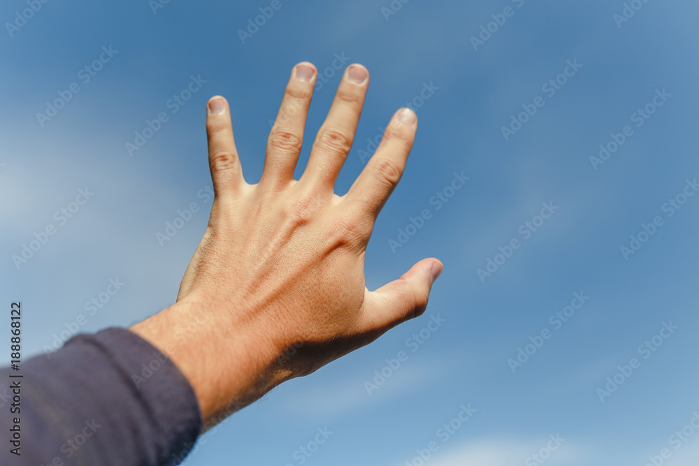 Hand palm on the blue sky with clouds Hand palm on the blue sky with clouds