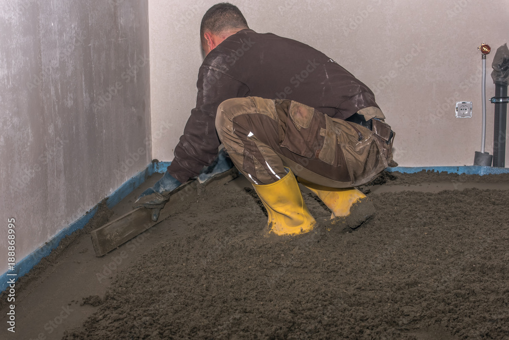 Screed flooring is processed in a residential building. A worker ...