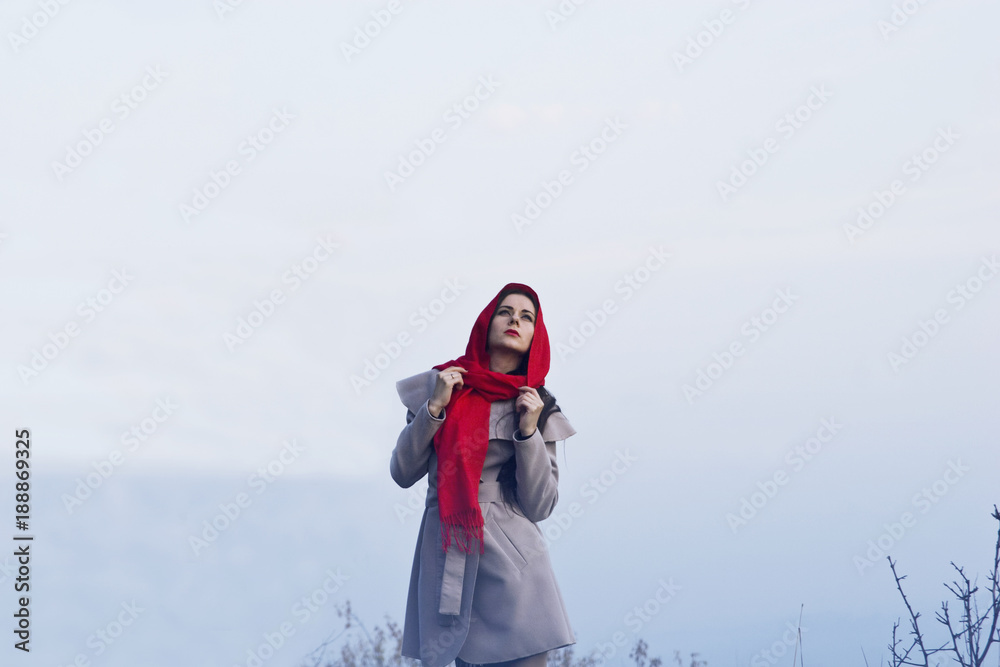 A girl in a red scarf in a blue mist on a rock A girl in a red scarf in a blue mist on a rock