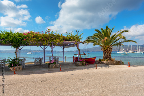 Restaurant tables in Adamas port and palm tree with beautiful view of the Adamas sea port. Milos, Greece. © vivoo