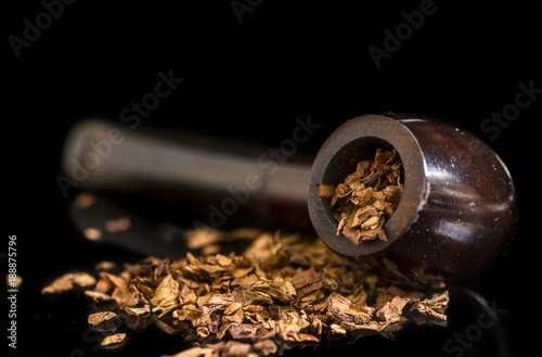 Tobacco Smoking pipe and tobacco spilled on a reflective glass surface, low key black background photo