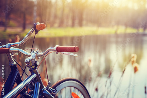 Two bikes standing on the shore of forest lake.