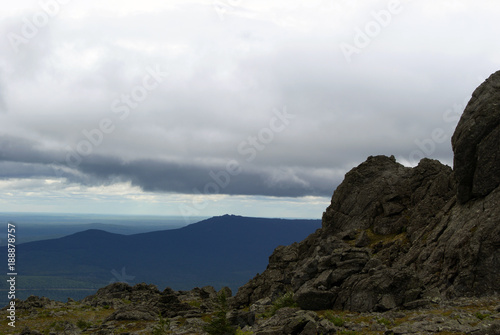 mountain landscape of the North Urals in summer in cloudy weather with a wrinkled, bumpy rock in the corner in the foreground..