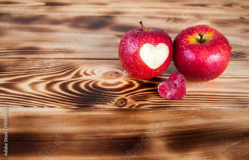 Red appes and cut out heart on burned boards photo