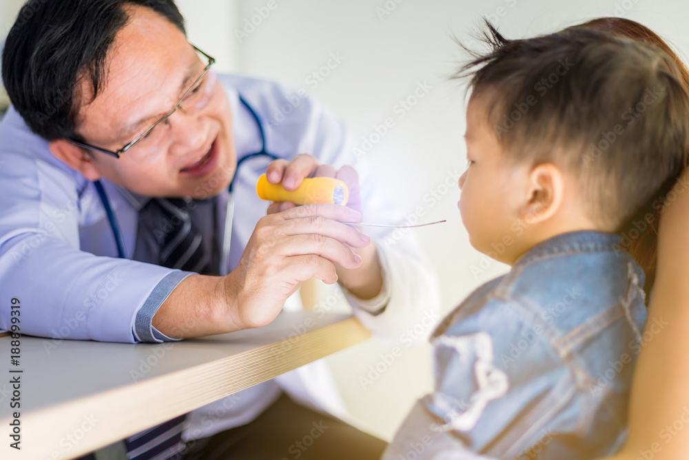 Doctor examines sick little boy throat with stainless tongue depressor Doctor examines sick little boy throat with stainless tongue depressor