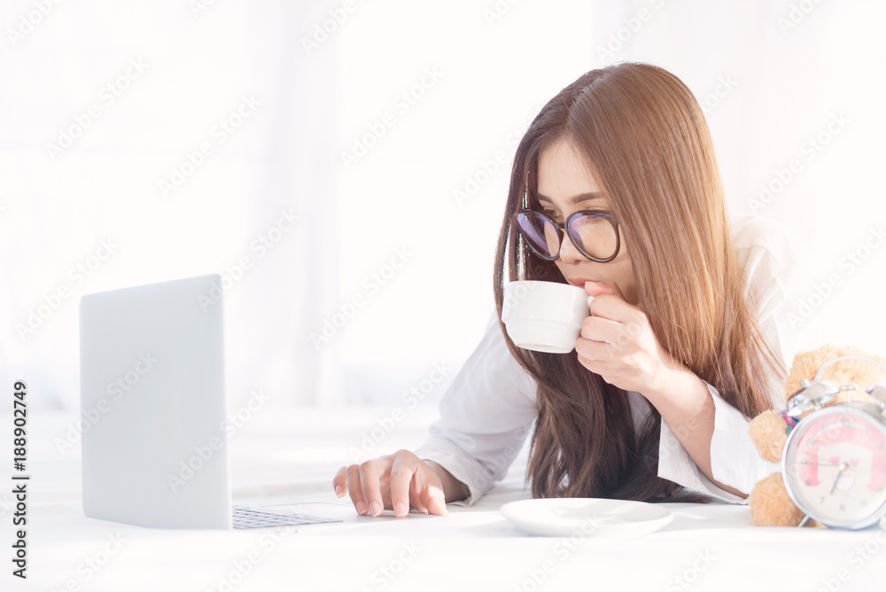 Portrait of a young business woman ,laptop,cup of coffee. Business concept a laptop drinking coffee with her computer on the bed Portrait of a young business woman ,laptop,cup of coffee. Business concept a laptop drinking coffee with her computer on the bed