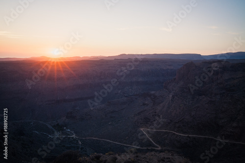 Sunset above mountains and canyon with rural road on bottom. © cegli