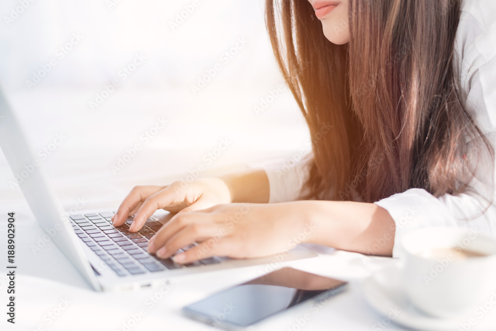 Fototapeta premium Portrait of a young business woman ,laptop,cup of coffee. Business concept a laptop drinking coffee with her computer on the bed