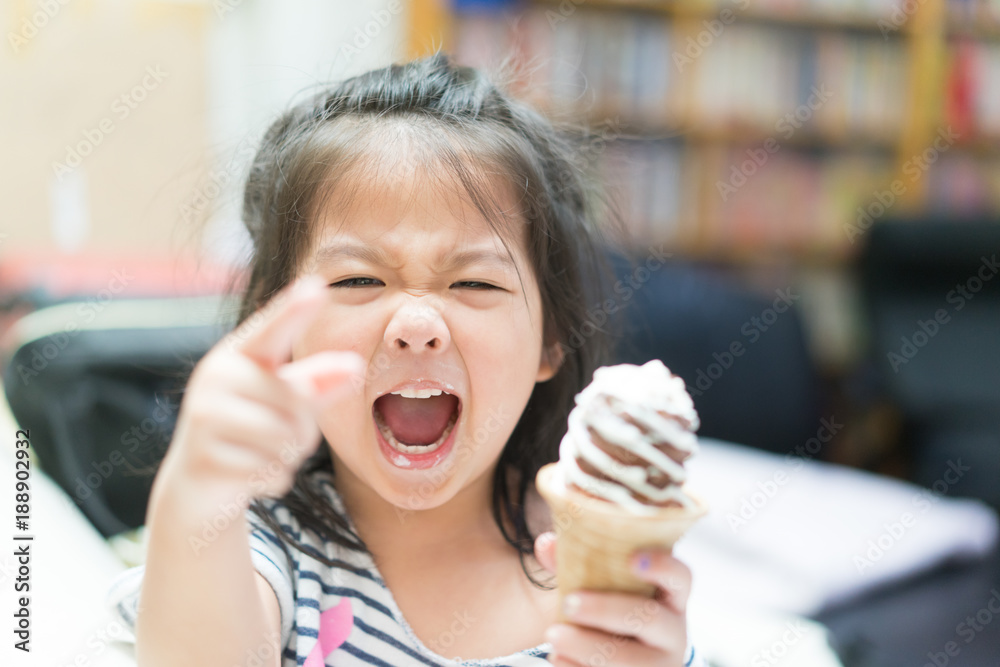 Happy Little asian girl eating soft cream or ice cream and she sit on sofa in living room. Happy Little asian girl eating soft cream or ice cream and she sit on sofa in living room.