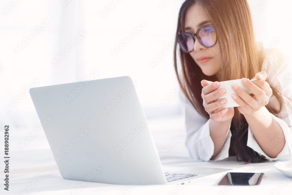 Portrait of a young business woman ,laptop,cup of coffee. Business concept a laptop drinking coffee with her computer on the bed