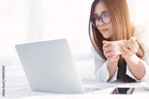 Portrait of a young business woman ,laptop,cup of coffee. Business concept a laptop drinking coffee with her computer on the bed
