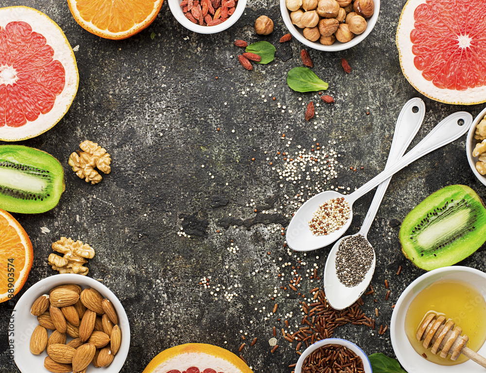 Ingredients of healthy dietary food breakfast pink grapefruit, orange, chia seeds, quinoa, green herbs, kiwi, wild rice, almonds, walnuts, hazelnuts on a gray background. The concept of natural