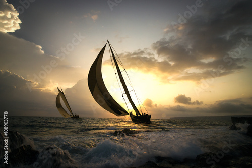 deux voiliers naviguent au soleil couchant