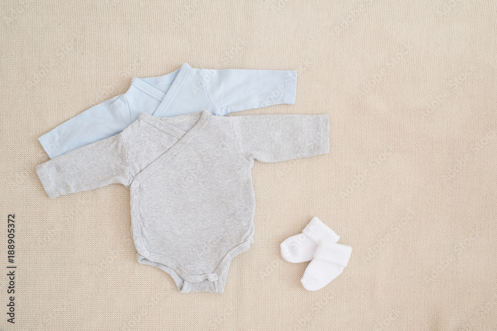 kleine Babysachen Body und weiße Strümpfe Studioaufnahme von oben auf wollenem Hintergrund
