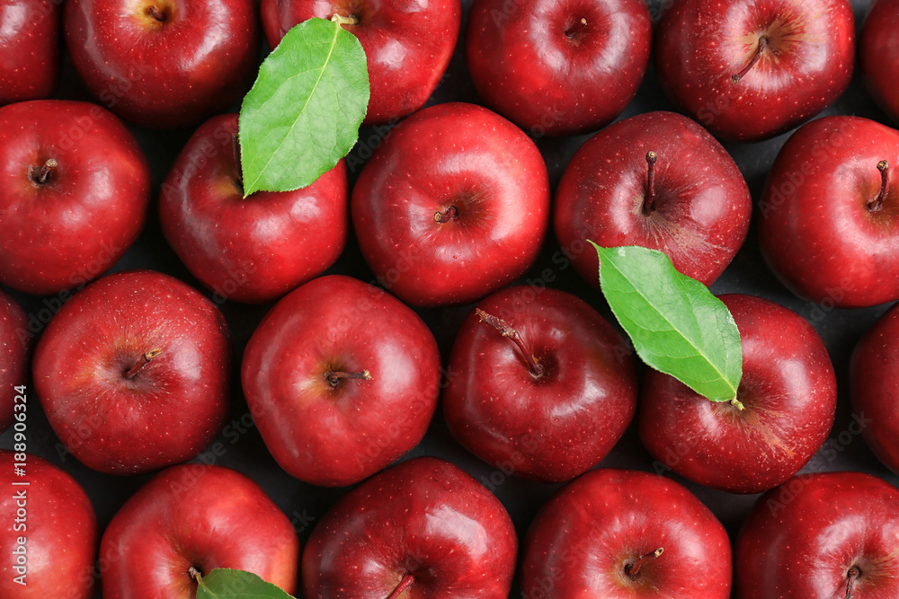 Fresh ripe red apples with green leaves as background - obrazy, fototapety, plakaty 