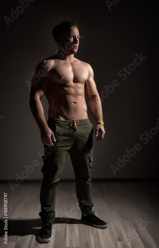 Strong athletic muscular man on dark background