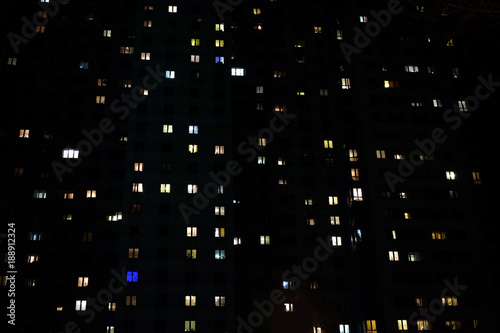 Facade of large multi-storey block of flats with many lighting windows in apartments at night front view © DyMaxFoto