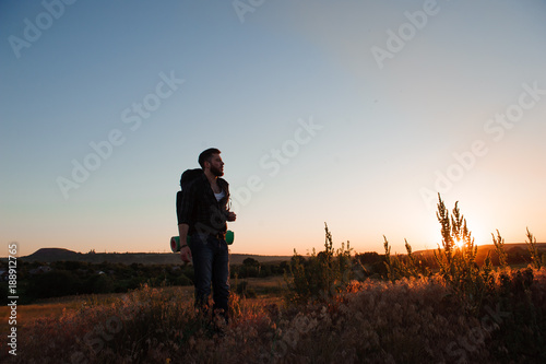 Traveler with backpack standing on a rock and enjoying sunset © nagaets