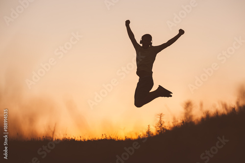 Silhouette of jumping man on sunset fiery sky background in mountain