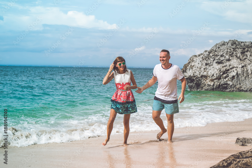 Happy young honeymoon couple having fun on the beach. Ocean, tropical vacation on Bali island, Indonesia.
