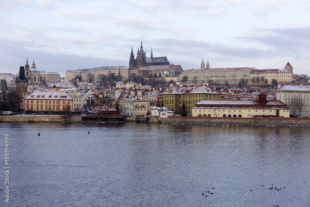 Fototapeta premium Snowy Prague Lesser Town with gothic Castle above River Vltava, Czech republic
