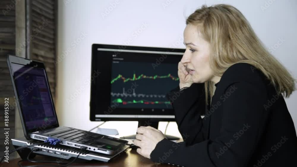 female trader talking on the phone and watching currency exchange chart at the computer monitor. Work on a crypto stock exchange female trader talking on the phone and watching currency exchange chart at the computer monitor. Work on a crypto stock exchange