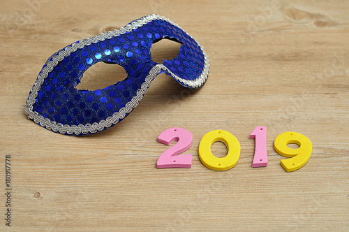 A blue masquerade mask with 2019 in colorful numbers