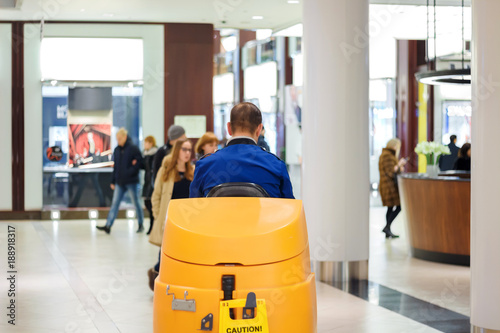 Cleaner in blue uniform on a sweeper in a shopping center photo