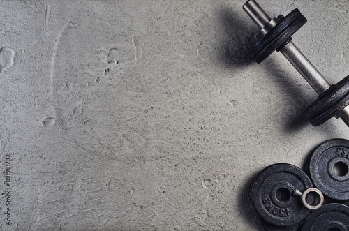 Fitness or bodybuilding concept background. Product photograph of old iron dumbbells on grey, conrete floor in the gym. Photograph taken from above, top view with lots of copy space