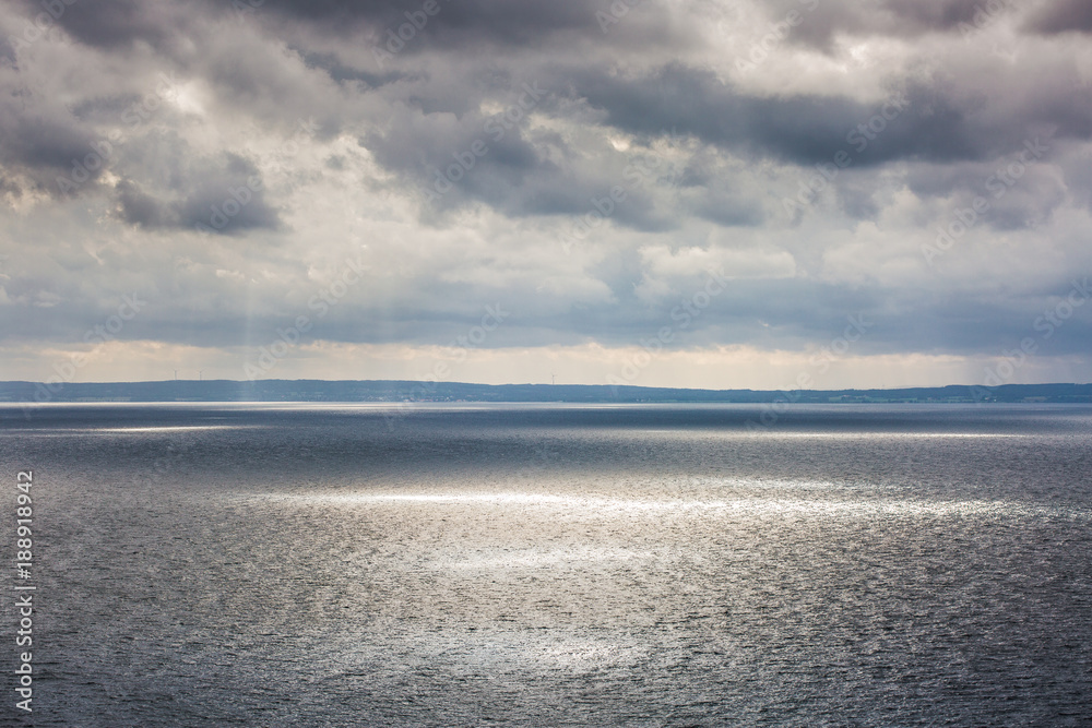 aerial view on the huge lake; sun rays struggle through the clouds making light sun spots on ripple water surface