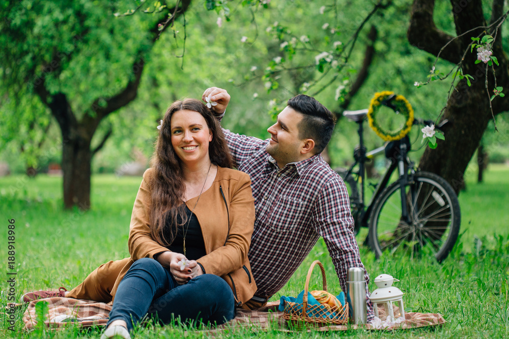 Young stylish happy couple in love having a picnic in blooming garden and  bicycle behind. Man putting flower in girlfriend's hair. Stock Photo |  Adobe Stock