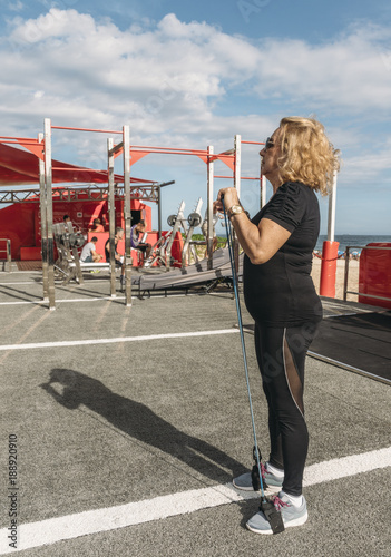 Mature woman (70-75) exercsing with a stretch cord at open air public gym in Ipanema Beach, Rio de Janeiro, Brazil photo