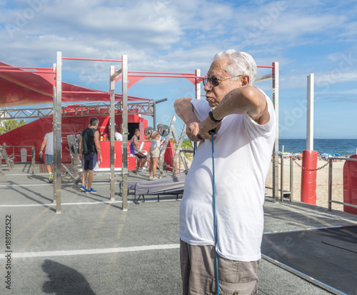 Older man (80-89) exercsing with a stretch cord at open air gym in Ipanema Beach, Rio de Janeiro, Brazil photo