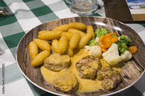 Steak beef and gravy sauce with boiled vegetable mix and fried potato on ceramic plate serve dinner in restaurant