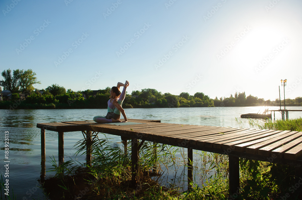 Young girl doing yoga fitness exercise outdoor in beautiful landscape. Morning sunrise. Meditation and Relax. Young girl doing yoga fitness exercise outdoor in beautiful landscape. Morning sunrise. Meditation and Relax.