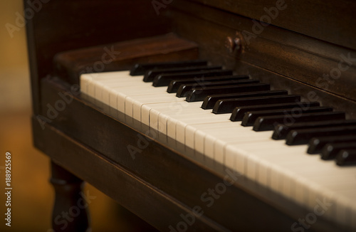 Close up of piano keys and old vintage wooden upright piano, shallow focus, warm brown tone